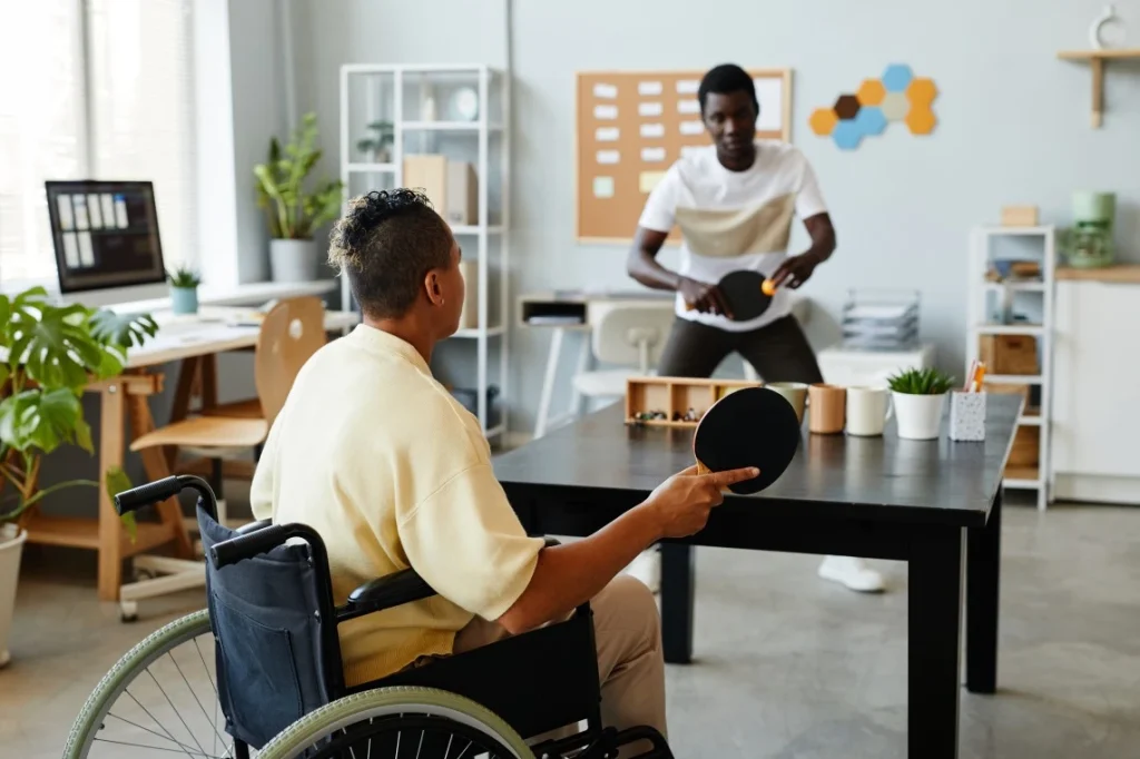 Disabled person in wheelchair playing table tennis with friend