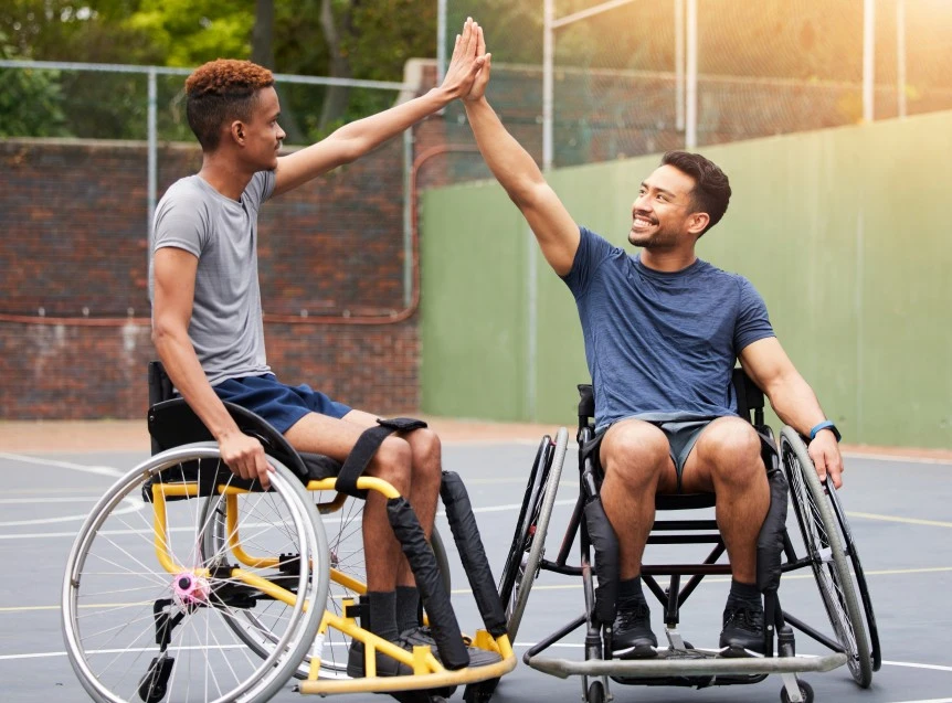Two disabled friends playing outdoor basketball and high fiving