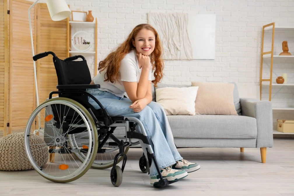Happy disabled woman sitting in wheelchair at home